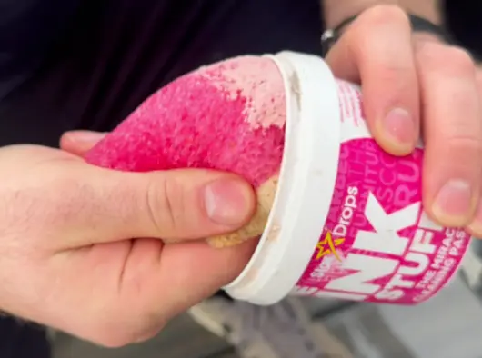 A guy picking up some Pink Stuff paste with a sponge to clean his bicycle.