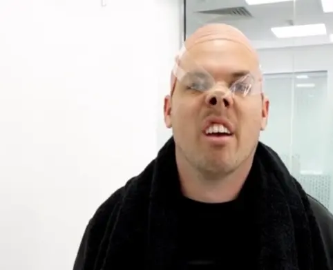 Liam Stapleton pretending to be Voldemort from Harry Potter by wearing a bald wig cap and using scotch tape to pull up his nose.