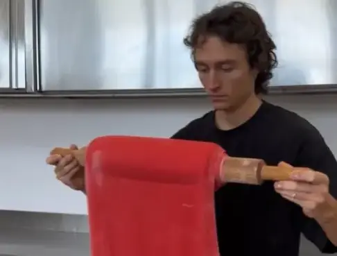 Magri Alberto rolling red dough in order to make lobster tail pastries.